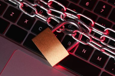 Siber güvenlik. Metal asma kilit, dizüstü bilgisayarda renk ışığı, üst görünüm.