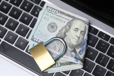 Siber güvenlik. Metal asma kilit ve dolar dizüstü bilgisayarda, üst görünümde.