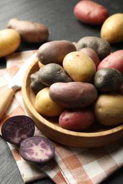 Kasede farklı patates çeşitleri ve siyah masada bıçak, yakın plan.