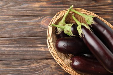 Tahta masada, sepetin içinde bir sürü olgun patlıcan var. Metin için boşluk