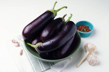 Beyaz masada bir sürü ıslak patlıcan, biber ve sarımsak.