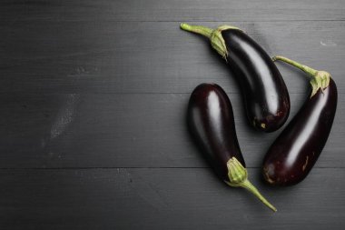 Siyah ahşap masada taze patlıcanlar, düz yatış. Metin için boşluk