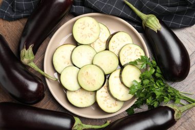 Etrafı maydanozlarla çevrili taze patlıcan dilimleri ve ahşap masanın üstünde düz bir şekilde yatıyordu.