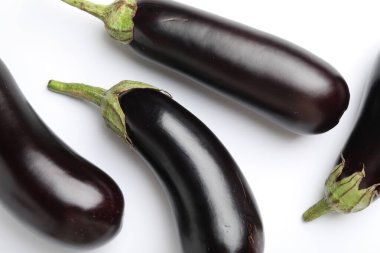 Beyaz arka planda bir sürü taze patlıcan var.