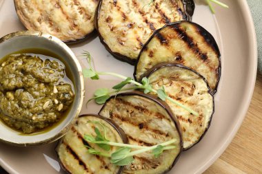 Soslu ızgara patlıcan dilimleri ve ahşap masada mikroyeşiller.