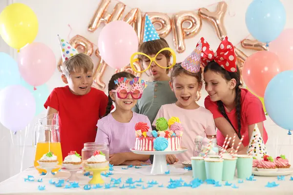 Doğum günü kutlaması. Masadaki çocuklar lezzetli pastalar ve dekoratif odalarda farklı şeyler yiyorlar.