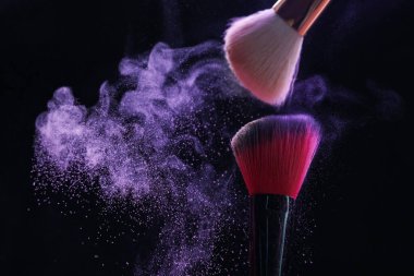 Siyah arka planda mor göz farlı makyaj fırçaları, yakın plan. Metin için boşluk