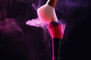 Renkli göz gölgeli makyaj fırçaları siyah arka planda neon ışıkları, yakın plan