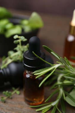 Ahşap masa üzerinde gerekli yağlar ve bitkiler, yakın plan.