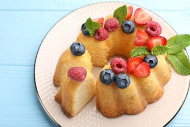 Açık mavi ahşap masada böğürtlenli ve nane şekerli Lezzetli Bundt keki.