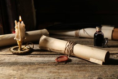Eski kağıt tomarlar ve yanan mumlar ahşap masada, yakın plan