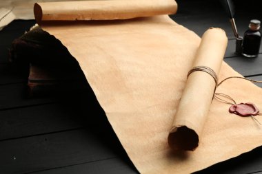 Eski tomarlar ve kitaplar siyah ahşap masada, yakın plan.