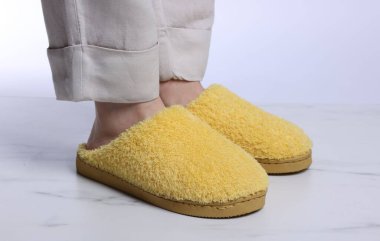 Beyaz mermer zeminde, yumuşak sarı terlikli kadın, yakın plan.