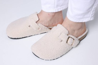 Aydınlık zeminde şık beyaz terlikli bir kadın, yakın plan.