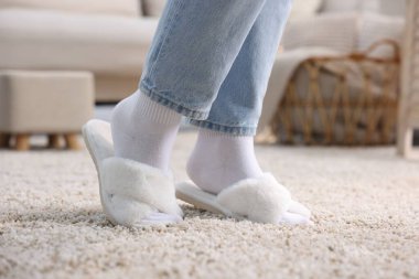Evdeki yumuşak halıda beyaz terlikli kadın, yakın plan.