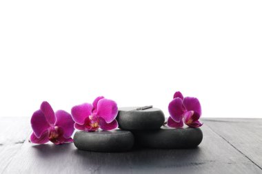 Akupunktur iğneleri, orkide çiçekleri ve beyaz arka plana karşı gri ahşap masa üzerindeki spa taşları