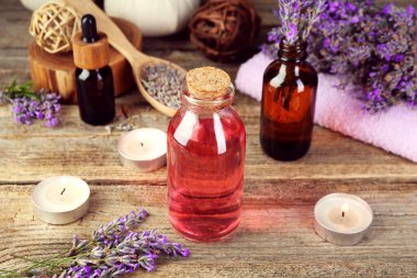 Lavanta yağı, çiçekler, mumlar ve havlu ahşap masada.