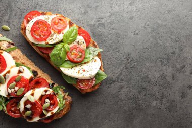 Mozarella peynirli lezzetli sandviçler ve gri masada domatesler, düz yatak. Metin için boşluk