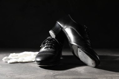 Step dansı için bir çift ayakkabı ve gri zeminde siyah arka planda beyaz eldivenler, yakın plan.