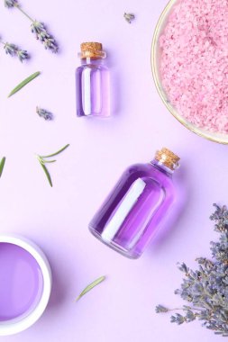Aromatik gerekli yağ, deniz tuzu ve mor arka planda lavanta çiçekleri, düz yatıyordu.