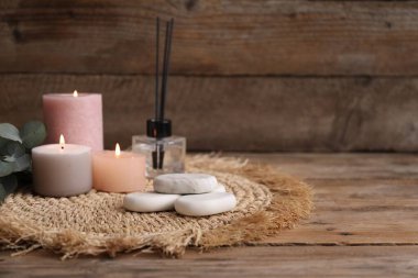Spa taşlı kompozisyon, kamış oda spreyi ve ahşap masada yanan mumlar, yakın çekim. Metin için boşluk