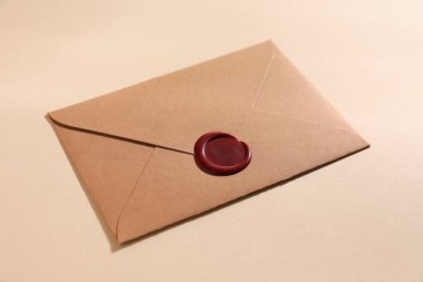 Bej arka planda kırmızı balmumu mühürlü güzel bir zarf, yakın plan.