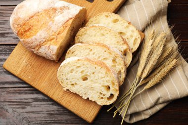 Taze ekmek ve buğday çivileri ahşap masada, düz yerde.