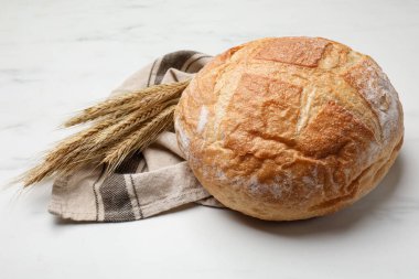 Beyaz mermer masada taze ekmek ve buğday çivileri, yakın plan.