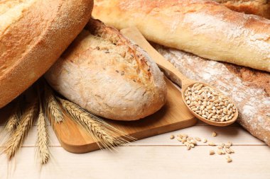 Tahta masadaki farklı ekmek, tahıl ve buğday çivileri, yakın plan.