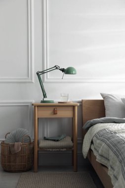 Yatak odasının yanında lamba ve bir bardak su olan komodinin yanında.