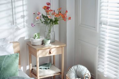 Yatağın yanında farklı dekorları olan bir komodin.