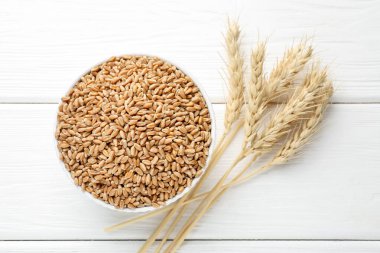 Kasede buğday taneleri, beyaz tahta masada çiviler, düz uzanmış.