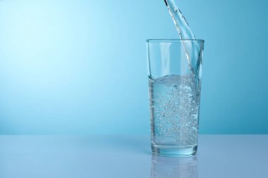 Açık gri ayna masasında, turkuaz gradyan arka plana, yakın planda, ferahlatıcı soda bardağına dökülüyor. Metin için boşluk