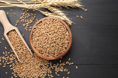 Kâsede buğday taneleri, siyah ahşap masada kepçeler ve çiviler düz yerde. Metin için boşluk