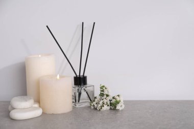 Açık gri masa üzerinde yanan mumlar ve sazlık dağıtıcı ile spa kompozisyonu, metin için boşluk