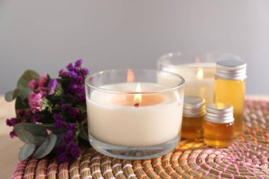 Yanan mumlar, çiçekler ve kozmetik ürünler gri arka planda, yakın plan