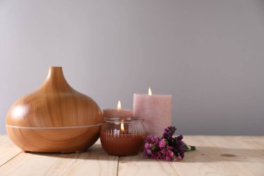 Çiçekli spa kompozisyonu ve ahşap masada yanan mumlar gri arka planda, yakın plan