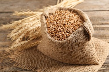 Çuval bezinde buğday taneleri ve tahta masada çiviler, yakın plan.