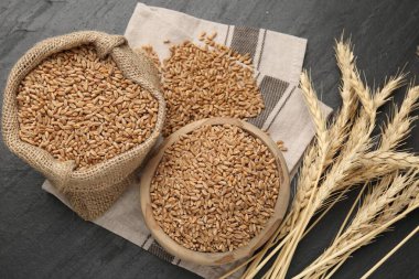 Kasede buğday taneleri, çuval bezi torbası ve siyah masada çiviler.