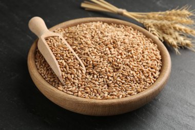 Kasede buğday taneleri, siyah masada kepçe ve çiviler, yakın plan.