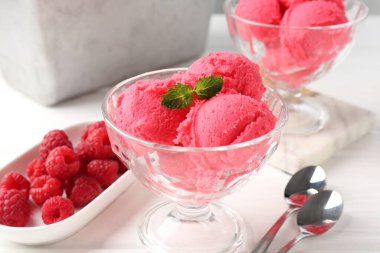 Tatlı kasesinde naneli ahududu şerbeti, beyaz ahşap masada kaşıklar ve taze meyveler, yakın plan.