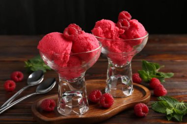 Tatlı kaselerinde nefis ahududu şerbeti, nane ve taze böğürtlen ahşap masada siyah arka planda, yakın planda.