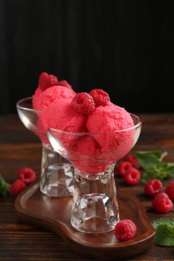 Tatlı kaselerinde nefis ahududu şerbeti, nane ve taze böğürtlen ahşap masada siyah arka planda, yakın planda.