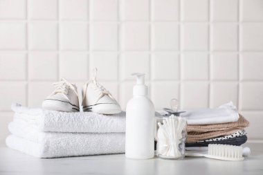 Duvarın yanındaki masada farklı bebek kıyafetleri ve aksesuarlar var.