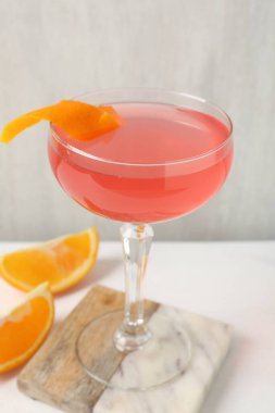 Martini kokteyli, garnitür ve portakal dilimleri beyaz masada, yakın plan.