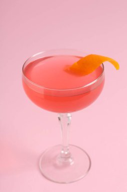 Pembe arka planda garnitürlü martini kokteyli, yakın plan.