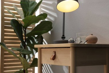 Bir bardak su, lamba ve bardaklı ahşap masa, yakın plan.