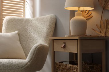 Şık ahşap sehpa. Evdeki koltuğun yanında lamba var. Yakın plan.