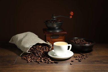 Kahverengi arka planda kahve, fasulye ve öğütücü ahşap masada.