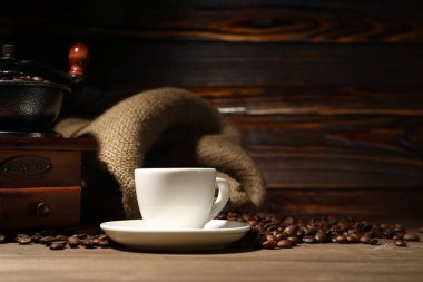 Bir bardak içki, kahve çekirdeği ve öğütücü ahşap masada.